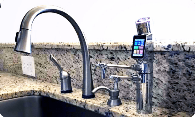 A kitchen sink with a phone on the faucet.
