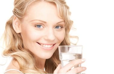 A woman holding a glass of water in her hand.