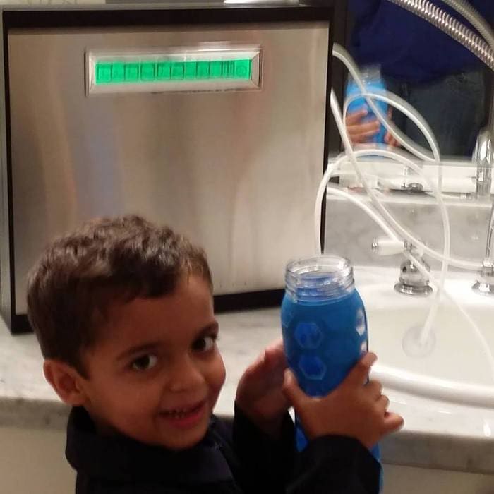 A young boy holding up a blue drink.